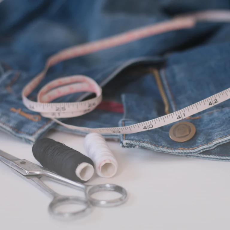 Scissors, thread and a measuring tape on denim, from the original Sewing Solutions website